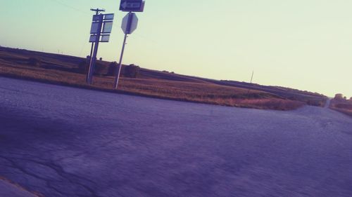 Road amidst field against clear sky