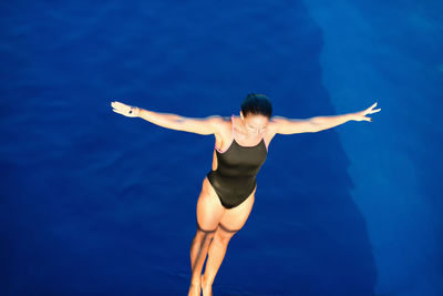 High angle view of woman with arms outstretched diving into swimming pool