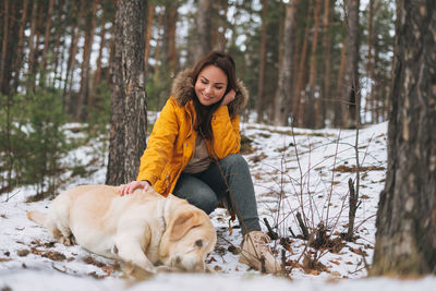 Woman with dog in forest during winter