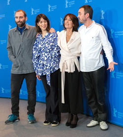 Portrait of friends standing against blue wall