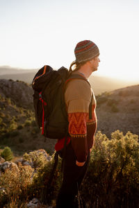 Man standing on rock against sky