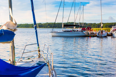 Sailboats moored in sea against sky