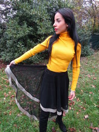 Beautiful young woman standing by tree