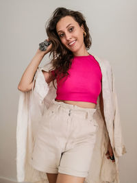 Portrait of a smiling young woman standing against wall