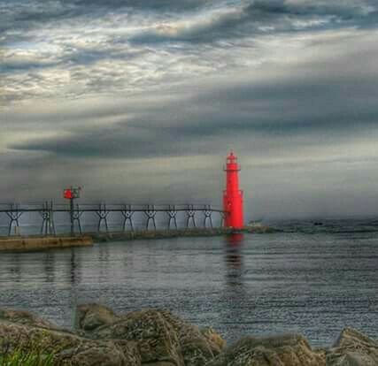 water, sky, sea, built structure, red, architecture, lighthouse, cloud - sky, cloudy, building exterior, guidance, safety, horizon over water, weather, protection, beach, cloud, shore, overcast, waterfront