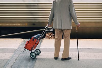 Low section of man walking with umbrella