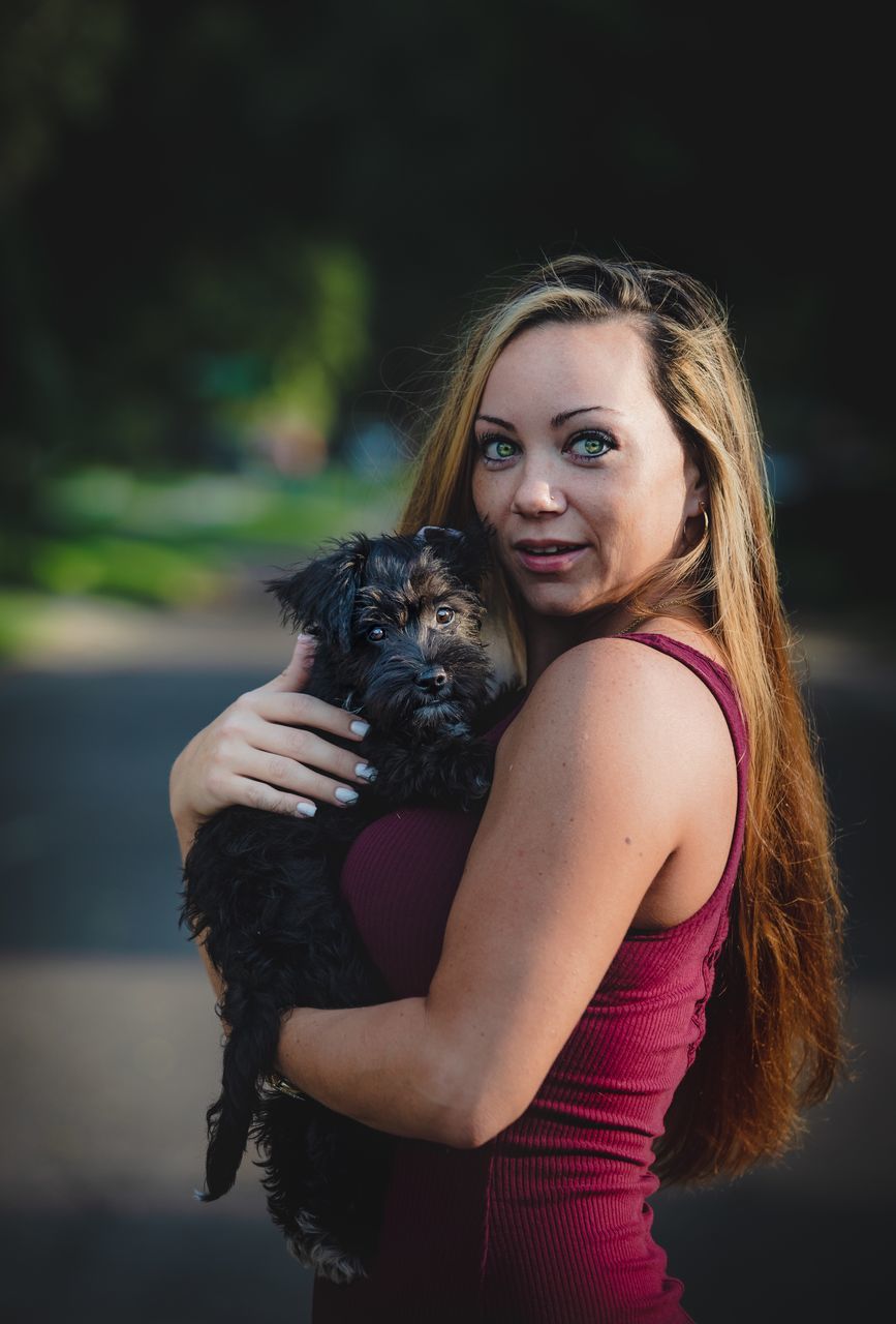 PORTRAIT OF YOUNG WOMAN WITH DOG ON RED