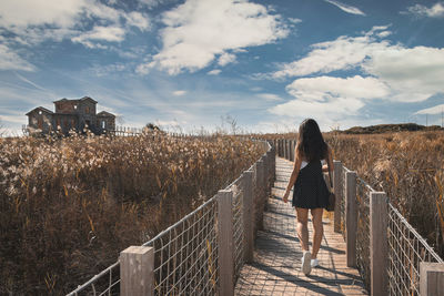 Rear view of woman walking on footpath amidst plants