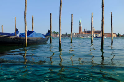 Wooden posts in sea with distant view of church of san giorgio maggiore against sky