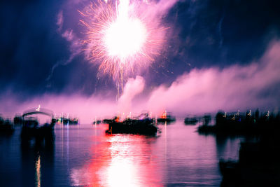 Firework display over river against sky at night