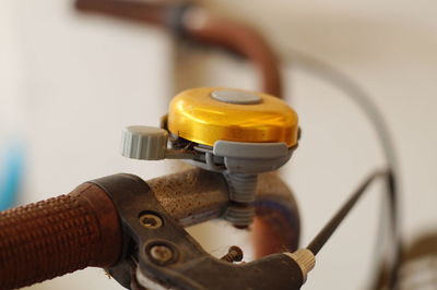 Close-up of golden bell on rusty handlebar