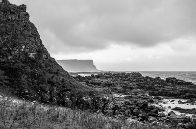 Scenic view of cliff by sea against sky