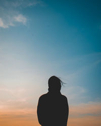Rear view of silhouette woman standing against sky during sunset