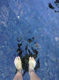 Low section of person standing in swimming pool