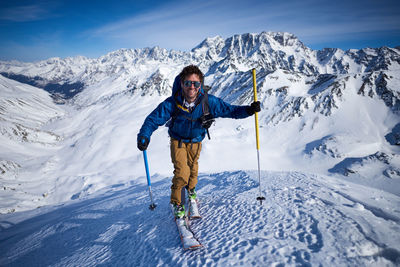 Smiling man ski touring up slope with mountains behind