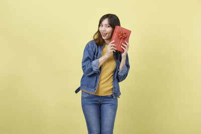 Portrait of smiling young woman against gray background