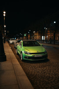 Cars on road by illuminated buildings in city at night