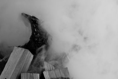 Low angle view of smoke emitting from wood against sky