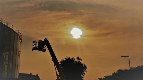 Low angle view of silhouette street light against orange sky