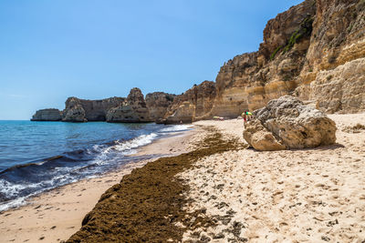 Rock formations on beach against clear blue sky