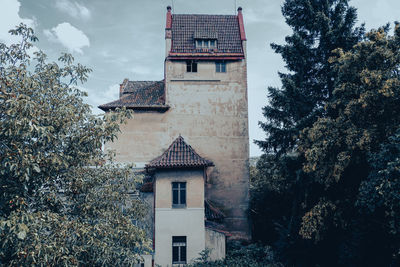 Low angle view of trees and building against sky