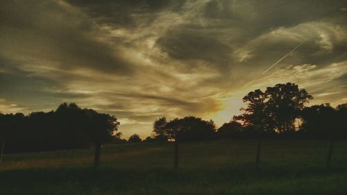 Scenic view of grassy field against sky at sunset