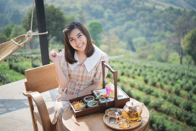 Portrait of smiling woman sitting on table