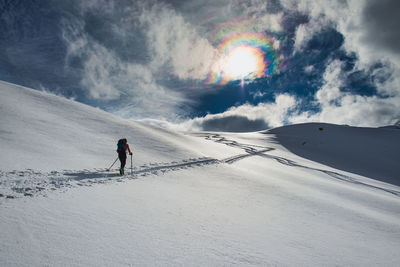 Man skiing on snowcapped mountain against sky