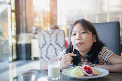 Portrait of girl eating food sitting at restaurant