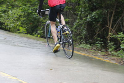 Low section of man riding bicycle on road