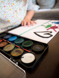 High angle view of palette on table while girl drawing