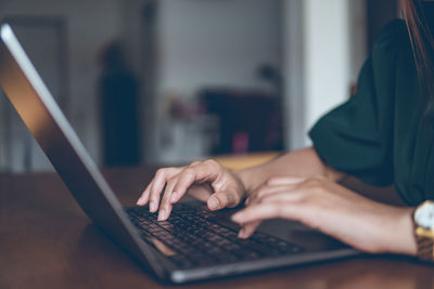 Close-up of man using laptop on table