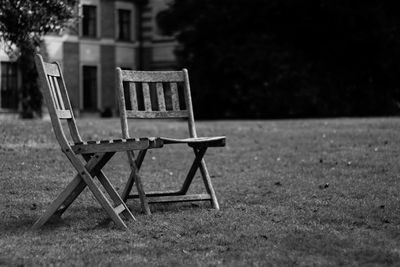 Empty wooden chairs on lawn in back yard