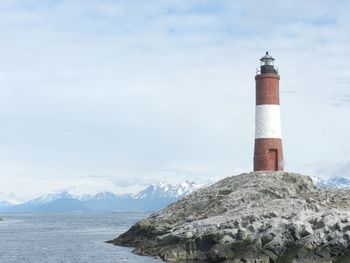 Lighthouse by sea against sky