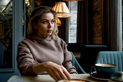 Middle-aged blonde caucasian woman drinks coffee in cafe