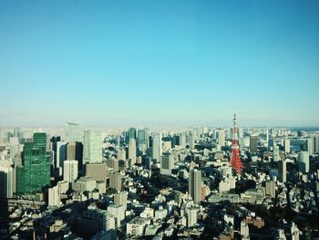 Aerial view of buildings in city against clear blue sky