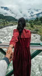 Boyfriend holding hand of girlfriend on bridge