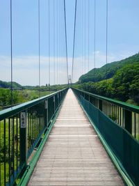 Footbridge amidst plants against sky