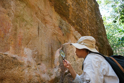 Rear view of woman standing against rock