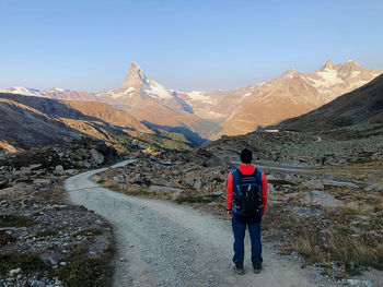 Rear view of man standing on mountain against sky