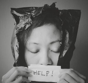 Close-up of woman holding help placard against black background