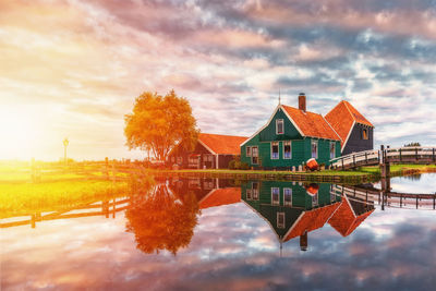 Reflection of houses and trees on lake against sky