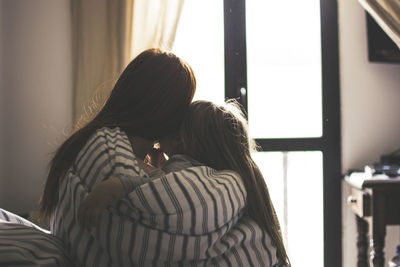 Rear view of woman and daughter covered in blanket at home