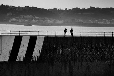 Low angle view of silhouette people walking on bridge