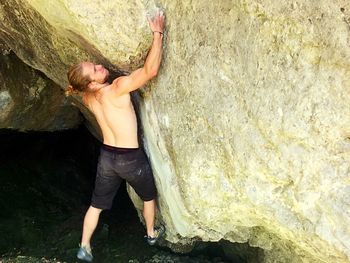 High angle view of shirtless man bouldering on rock