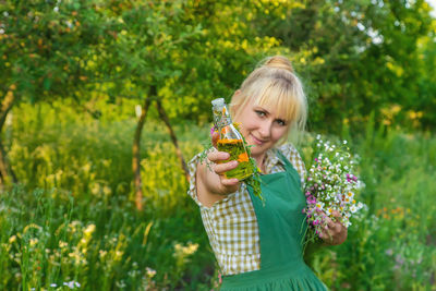 Portrait of young woman standing against plants