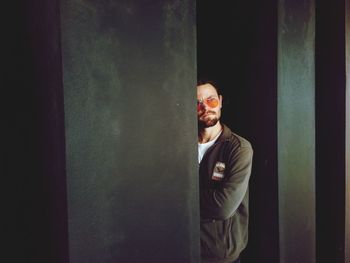 Young man looking away while standing against wall