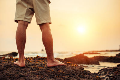 Low section of man standing on beach