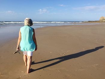 Rear view of woman walking at beach