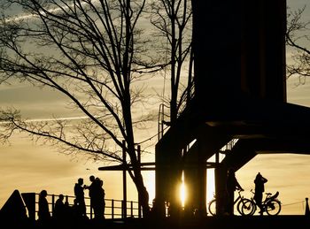 Silhouette people on street against sky during sunset